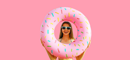 Summer vacation, tourism, happy cheerful young woman with swimming inflatable ring on studio pink...