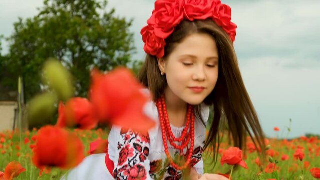 A young beautiful girl in a flowering poppy field. The girl inhales the scent of poppy flowers. The concept of freedom. Close-up