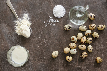 Quail eggs in a bowl on the dark stone table. Group of quail eggs with  flour, salt, milk.