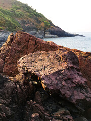 Red colored textured rock on Sinquerim beach of North Goa, India.
