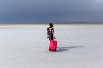 The girl with the red. with a suitcase on the Kazakh Salt Marsh