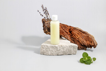 cosmetics container on the podium made of stone, tree bark, lavender twigs and mint leaves on a...