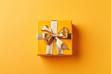 Gift box with golden satin ribbon and bow on yellow background, Holiday gift with copy space. Birthday or Christmas present, flat lay, top view. Christmas giftbox concept, created with Generative AI