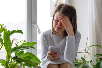 frustrated sad young woman looking at smartphone, reading bad news, crying received of new information. abandoned teenager girl cries for unhappy love