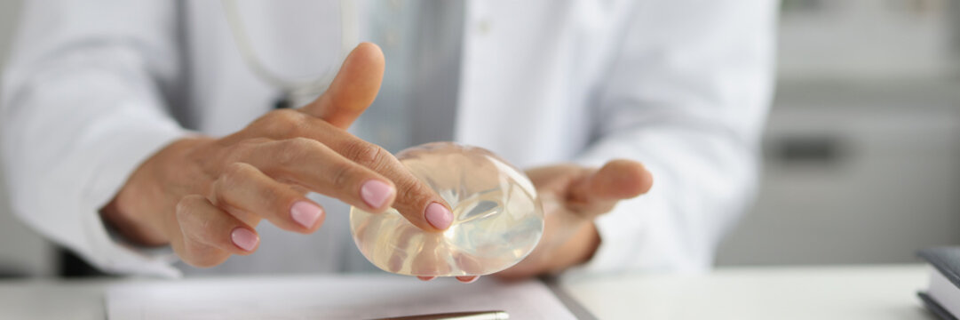 Female plastic surgeon touching silicone implant with finger