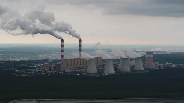 Aerial view of power plant, smoke from chimneys and open-cast coal mine in Belchatow under moody cloudy sky, Poland