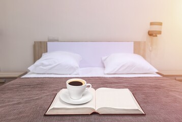 Morning coffee cup and book on bed