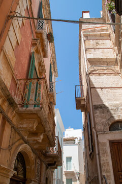 La estrechez de las calles del casco antiguo, calle Annunziata en Polignano a Mare, Italia. Casas antiguas de estructura tradicional muy apretadas para dar sombra durante el sofocante verano.