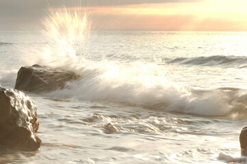 Ocean waves spashing against rocks at sunset