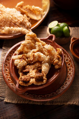 Chicharron. Crispy Fried pork rind, are pieces of aired and fried pork skin, traditional Mexican ingredient or snack served with lime juice and red hot sauce.