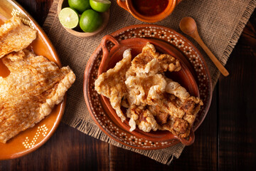 Chicharron. Crispy Fried pork rind, are pieces of aired and fried pork skin, traditional Mexican ingredient or snack served with lime juice and red hot sauce.