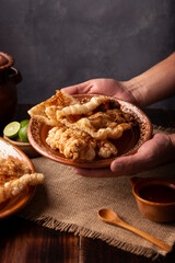 Chicharron. Crispy Fried pork rind, are pieces of aired and fried pork skin, traditional Mexican ingredient or snack served with lime juice and red hot sauce.