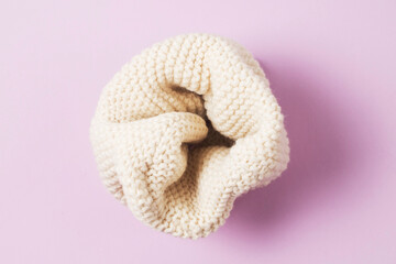 White knitted snood on lilac background top view