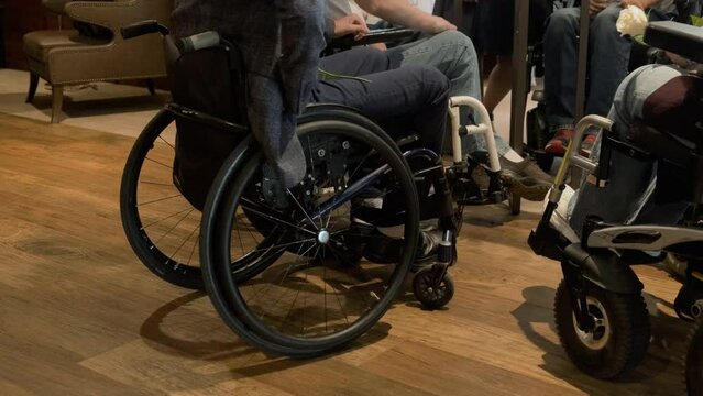 Disabled entrepreneurs sit in wheelchairs and communicate at a business conference. Accessible environment, diversity. Unrecognizable