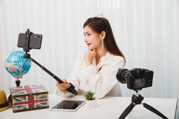 Young asian woman blogger selfie herself with smart phone while recording vlog video live...