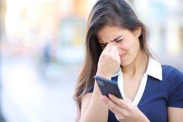 Woman suffering eyestrein holding phone