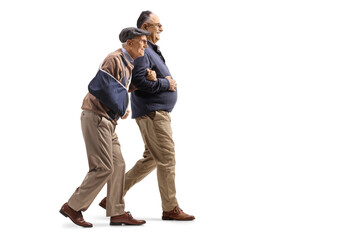 Naklejka premium Man walking with a senior man with an injured arm in a sling