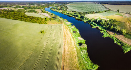 The view has fields, meadows, forests and a river from above. Greater Poland Voivodeship. Drone aerial - obrazy, fototapety, plakaty