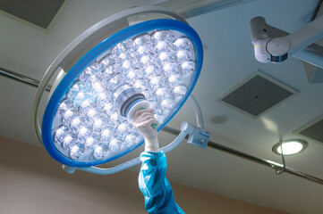 Surgeon's hand moving the lamps in the operating room at the hospital. light bulb health concept