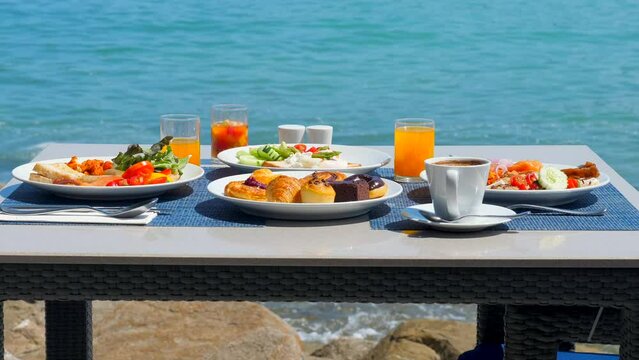 Delicious breakfast on coast, surrounded by the stunning views of the beach. Variety of fresh food on set table at luxury seaside restaurant.