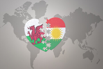 puzzle heart with the national flag of kurdistan and wales on a world map background.Concept.