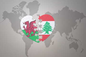 puzzle heart with the national flag of lebanon and wales on a world map background.Concept.