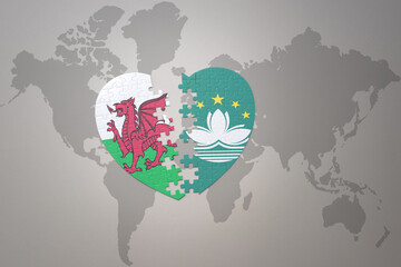puzzle heart with the national flag of Macau and wales on a world map background.Concept.