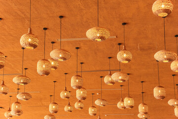 Stylish irregular straw like lamp shades on orange ceiling