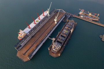 Dry dock with Cargo Ship maintenance or repair at floating dock in shipyard both deck crane loading...