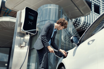 Below view closeup image of progressive black suit businessman recharge battery of his electric...