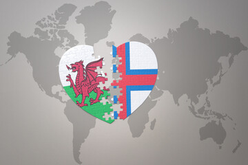 puzzle heart with the national flag of faroe islands and wales on a world map background.Concept.