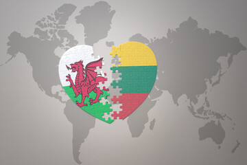 puzzle heart with the national flag of lithuania and wales on a world map background.Concept.