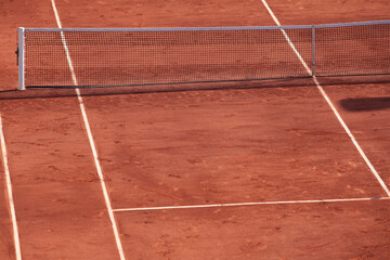 Fragment of clay tennis open court with footsteps. Grid and marking lines visible. Tennis net....