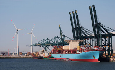 Port of Antwerp, Belgium - 25-05-2023: Large container vessel in the port with wind generators in the background.