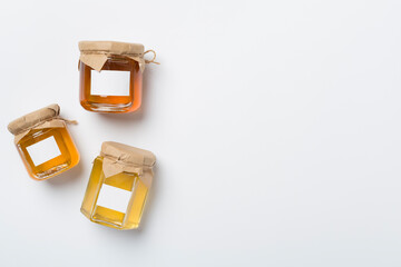 Jars with different honey on white background, top view. Mock up design