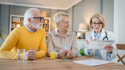 Home visit female doctor with senior man and woman couple at home talk