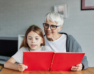 grandchild family child grandparent grandmother book reading elderly granddaughter girl  happy...