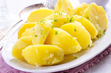 Traditional boiled potatoes with chives service es close-up on a classic design plate