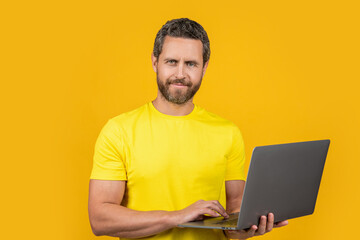 happy man blogger in studio. photo of man blogger with laptop. man blogger isolated on yellow.