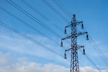 The low-angle view of a transmission tower with electric wires under the blue sky