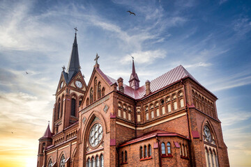 Cathedral of the Immaculate Virgin Mary in Jelgava city, Latvia under the sunset sky. Birds flying in the sky.