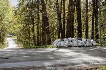 Pollution of nature. Garbage bags was dropped in the woods near the road.