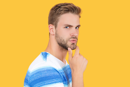 young caucasian millennial man or guy face portrait touch beard isolated on yellow studio background