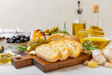 Italian ciabatta bread cut in slices with herbs, olives, pesto sauce, garlic and parmesan cheese on...