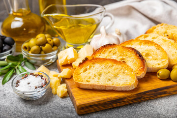 Italian ciabatta bread cut in slices with herbs, olives, pesto sauce, garlic and parmesan cheese on a concrete table. Fresh homemade Italian Ciabatta bread sliced with herbs and spices.Place for text.