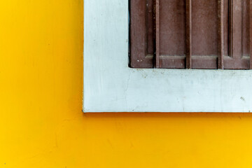 The yellow wall adorned with a half wooden window, gives the room a lively warmth and a welcoming atmosphere.