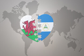 puzzle heart with the national flag of nicaragua and wales on a world map background.Concept.