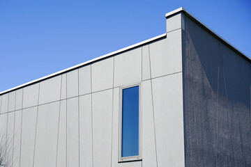Fototapeta na wymiar Abstract new modern residential house gray facade fragment against a blue sky