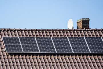Photovoltaic solar panels mounted on residential house brown metallic tiles roof