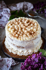 Sweet dessert for the whole family: A cake with vanilla cream on a wooden base, on a gray background. Vertical photo. Close-up